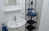 Bad mit Badewanne und Duschvorhang, WC, Spültisch und Spiegel